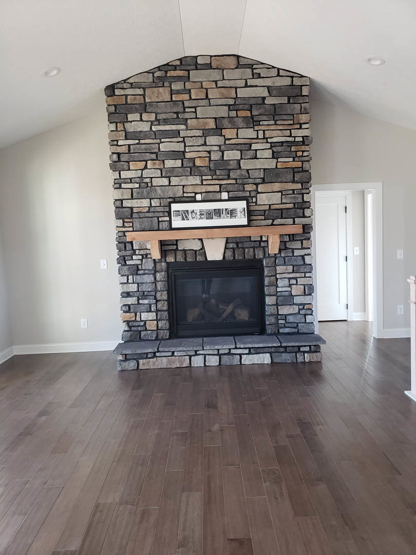 Modern living room with wood flooring, black-framed glass fireplace, white door with black handle, and framed artwork on the mantle