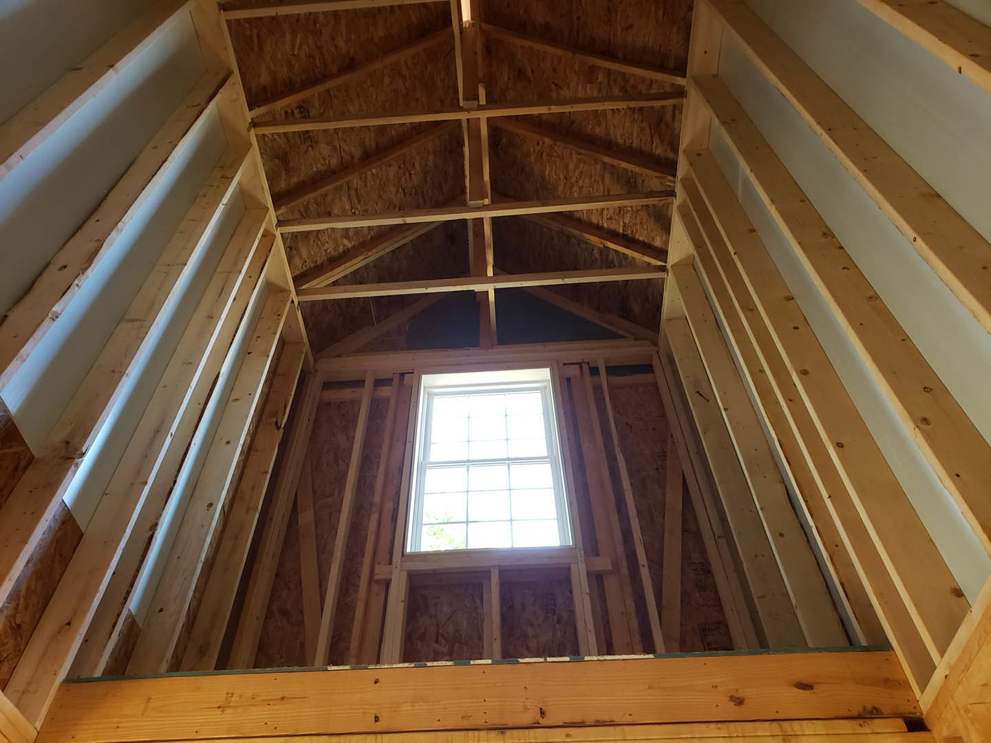 Sunlit room featuring a large window with wood trim, hardwood flooring, exposed ceiling beams, and symmetrical molding details.