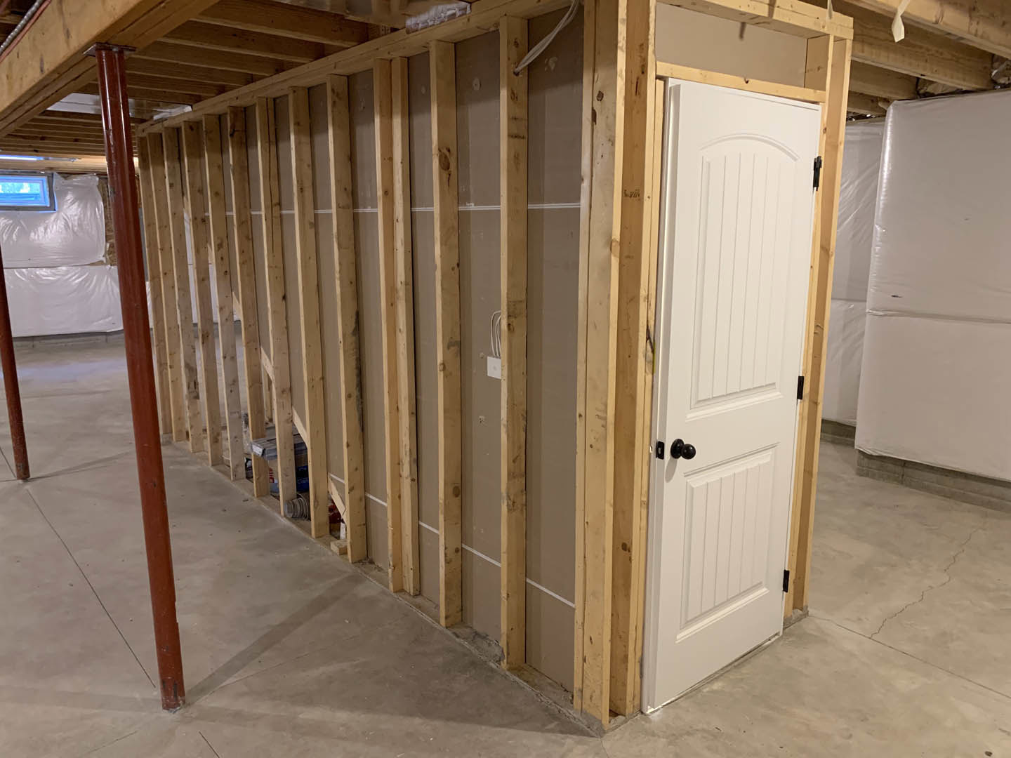 White paneled door with brushed metal handle set in a neutral-toned room, wood plank flooring, and smooth painted walls