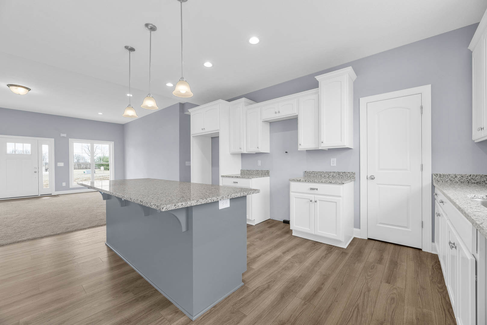 Granite island with undermount sink, white shaker cabinets, stainless steel appliances, light tile flooring, recessed lighting, and white paneled doors