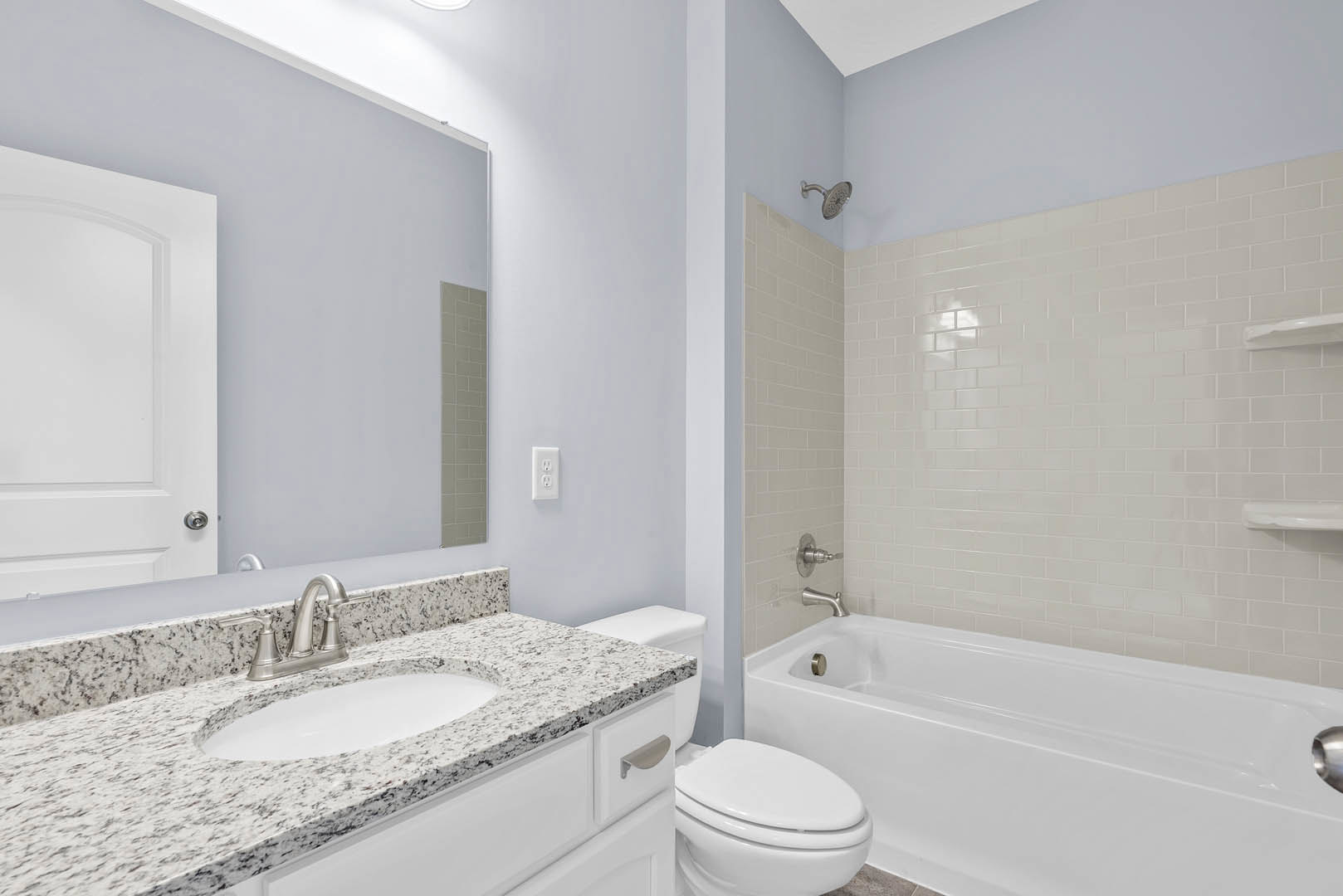Modern bathroom featuring a white freestanding tub against a tiled wall, a rectangular sink with a black faucet, and a white toilet with the seat down.