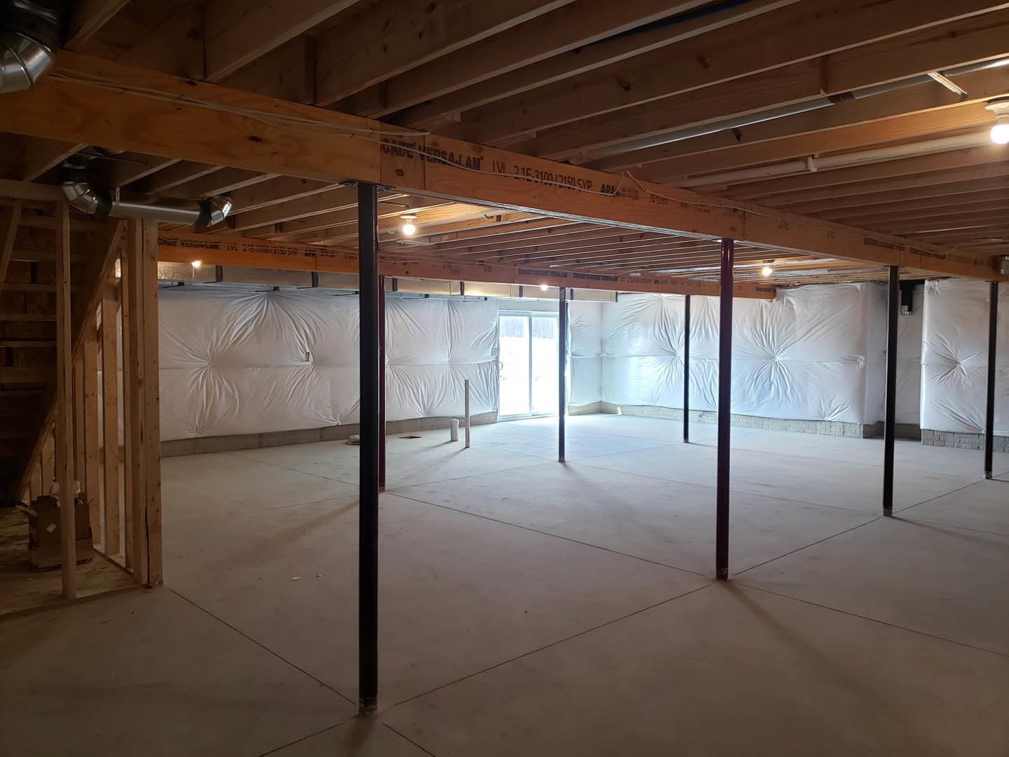Wood plank ceiling with exposed black beam, white walls, polished concrete floor, black metal pole, minimal furnishings including a white pillow with black frame, white bag hanging