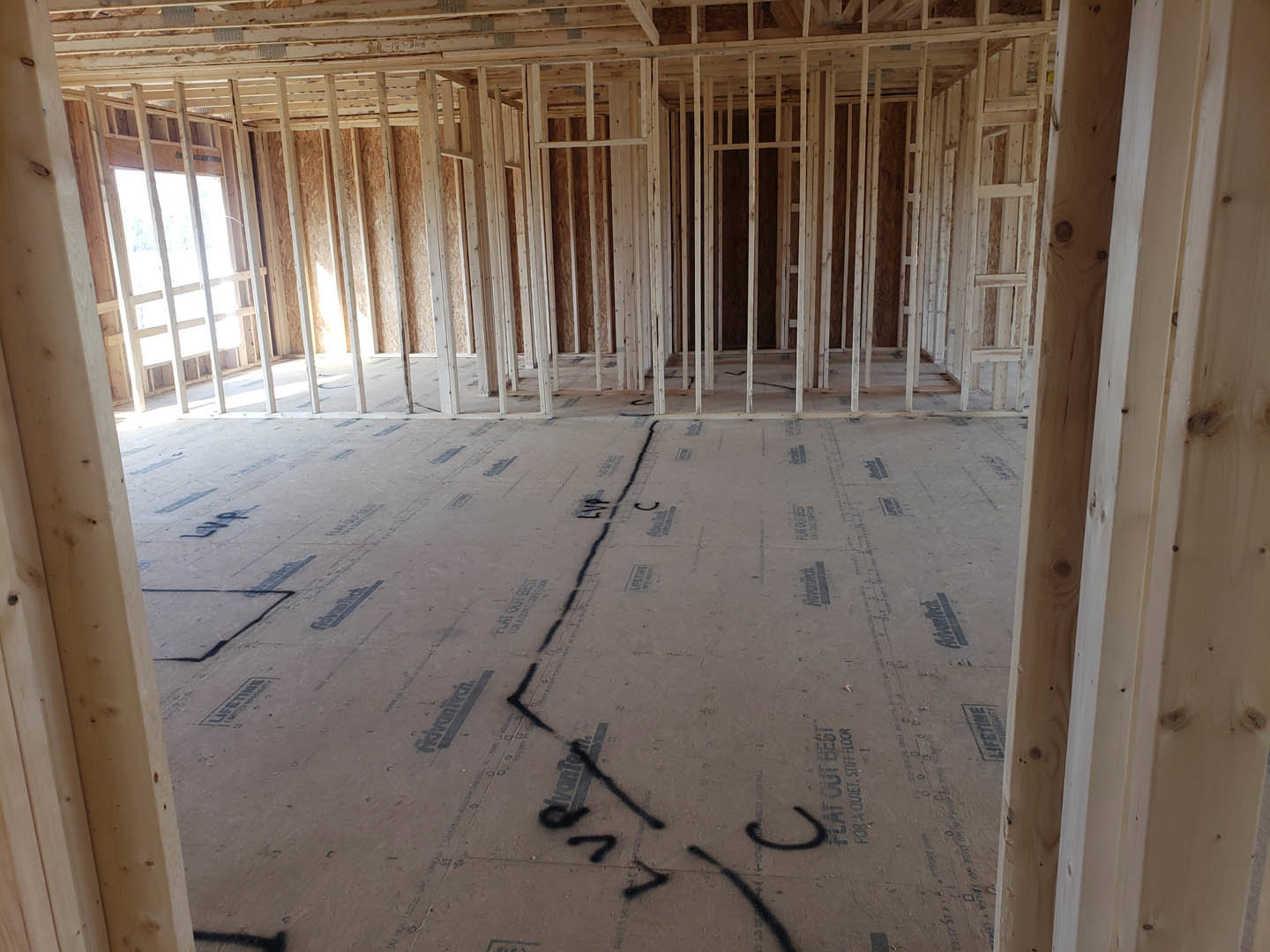 Room with exposed wood framing, black painted floor, and visible window frame