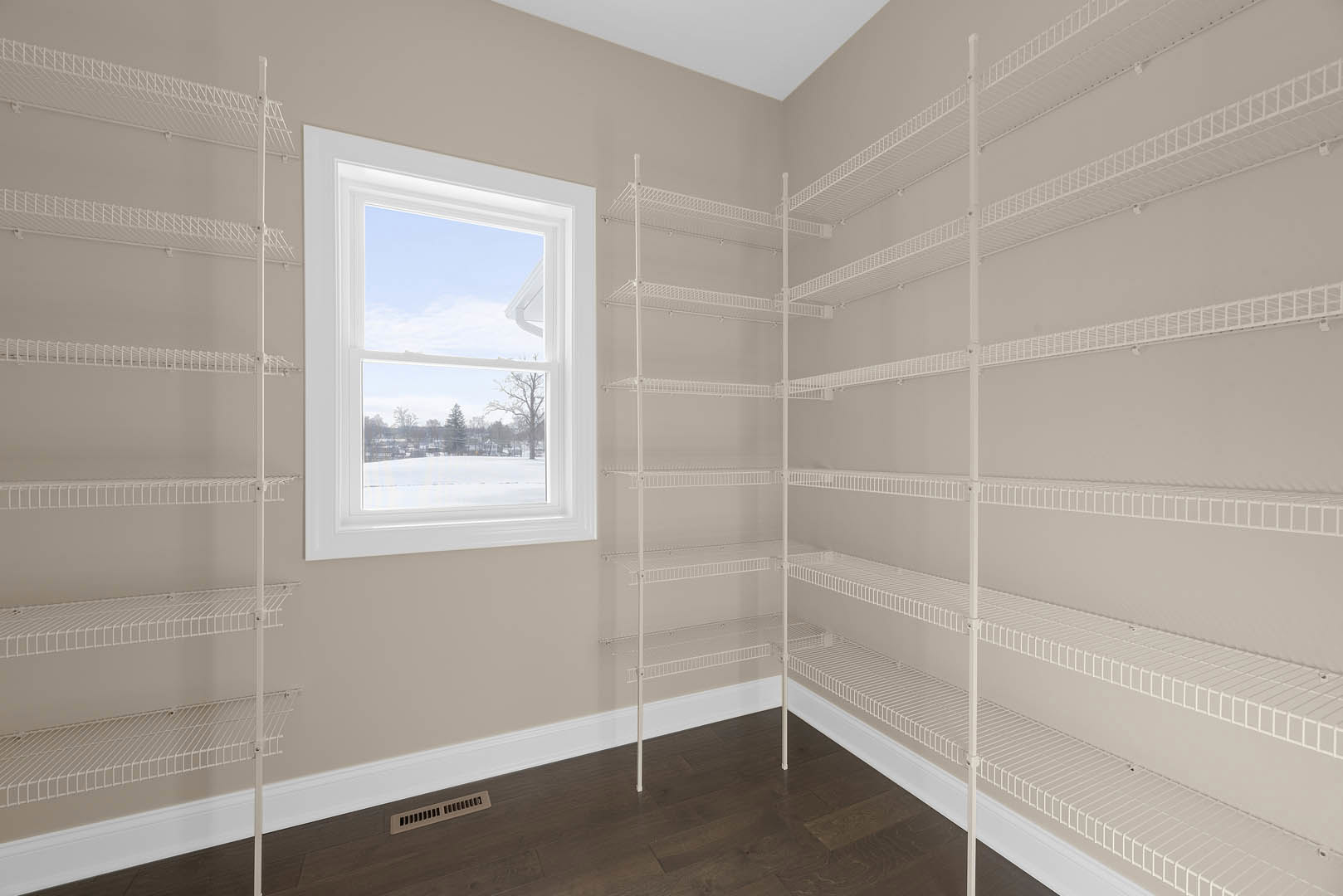 White wire shelving unit along plaster wall, wood floor, large window with snowy landscape view, ceiling vent visible