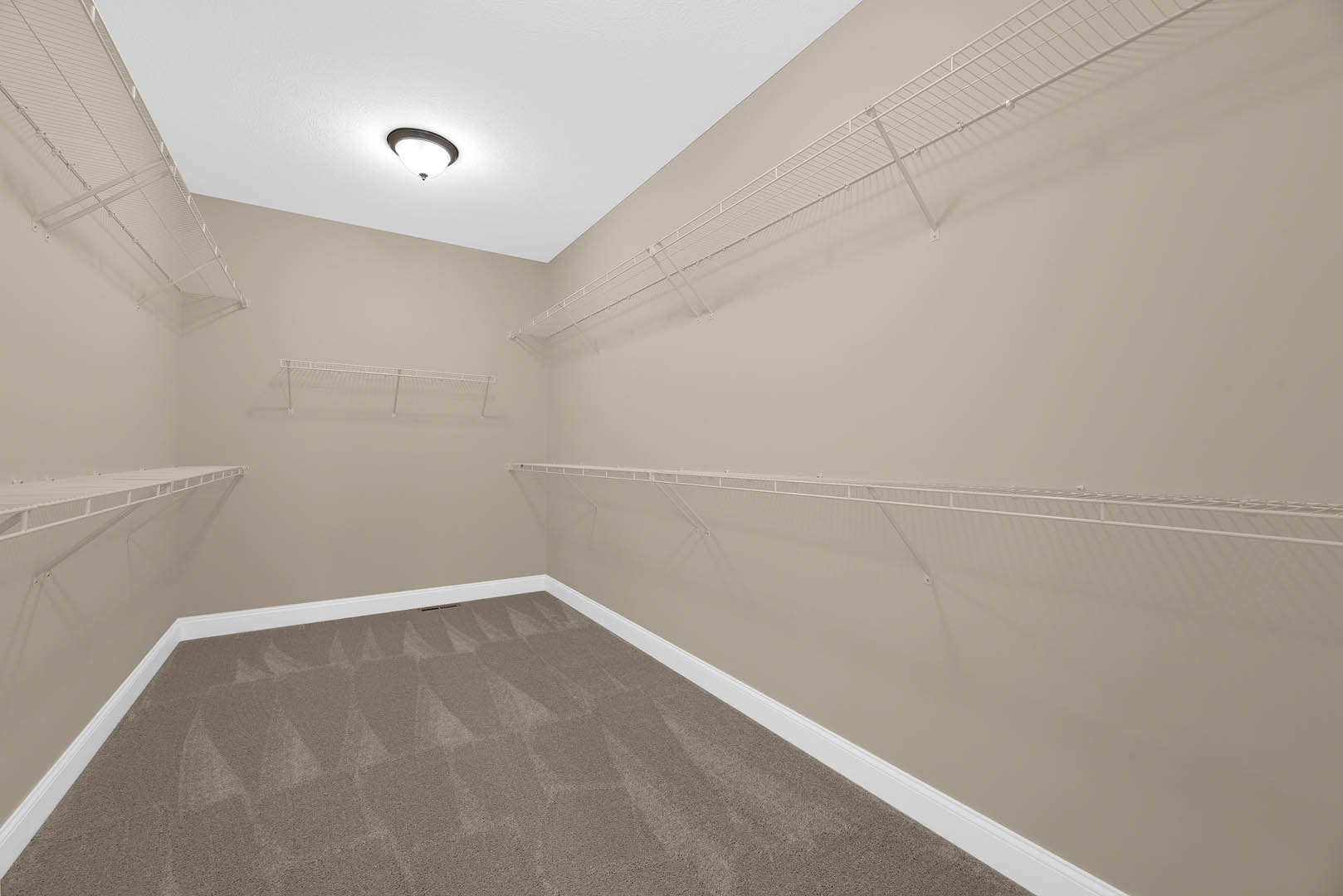 Carpeted room with built-in white shelves, white plaster ceiling, recessed lighting, and metal railing along one wall