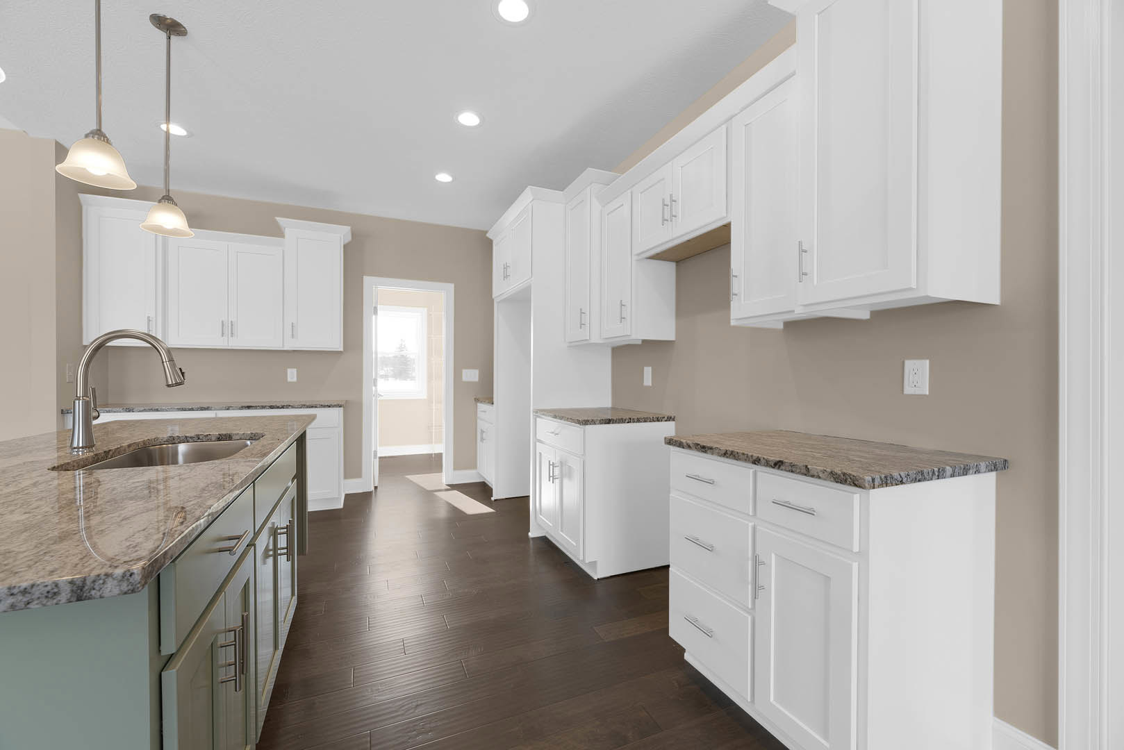 White kitchen with marble-topped island, white cabinetry, dark wood flooring, stainless steel faucet, ceiling light fixture, and door with window.