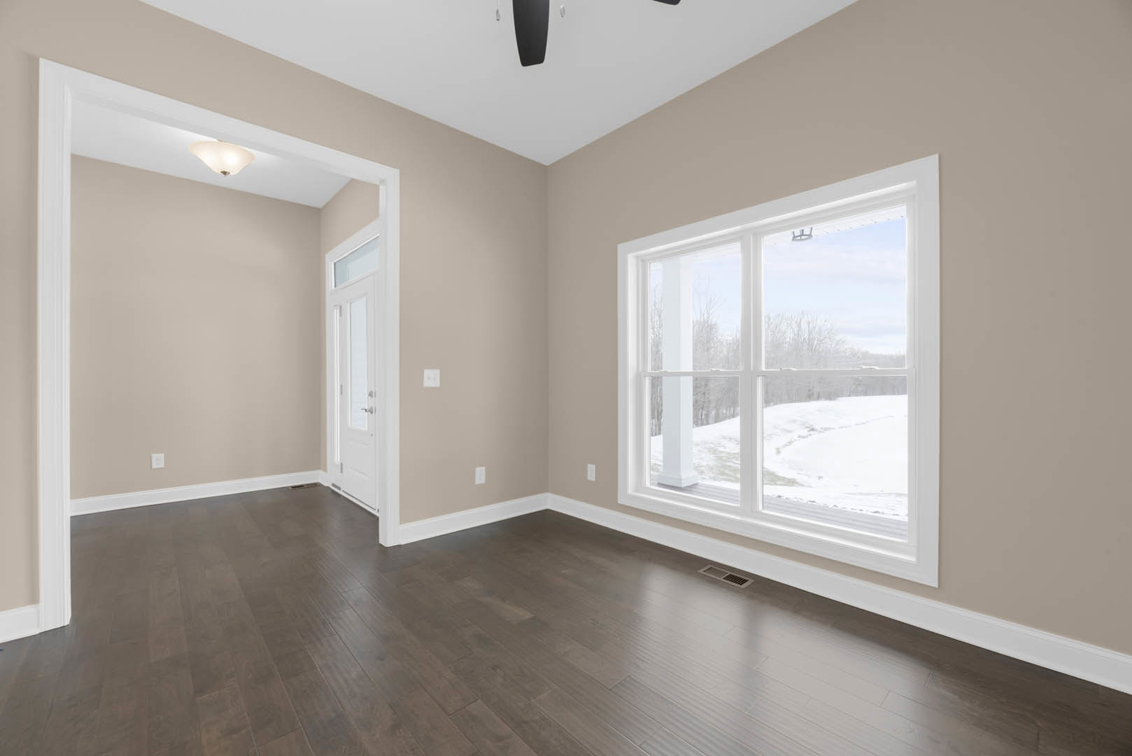 Room with dark wood flooring, large window overlooking snowy landscape, white plaster walls, decorative molding, and ceiling light fixture