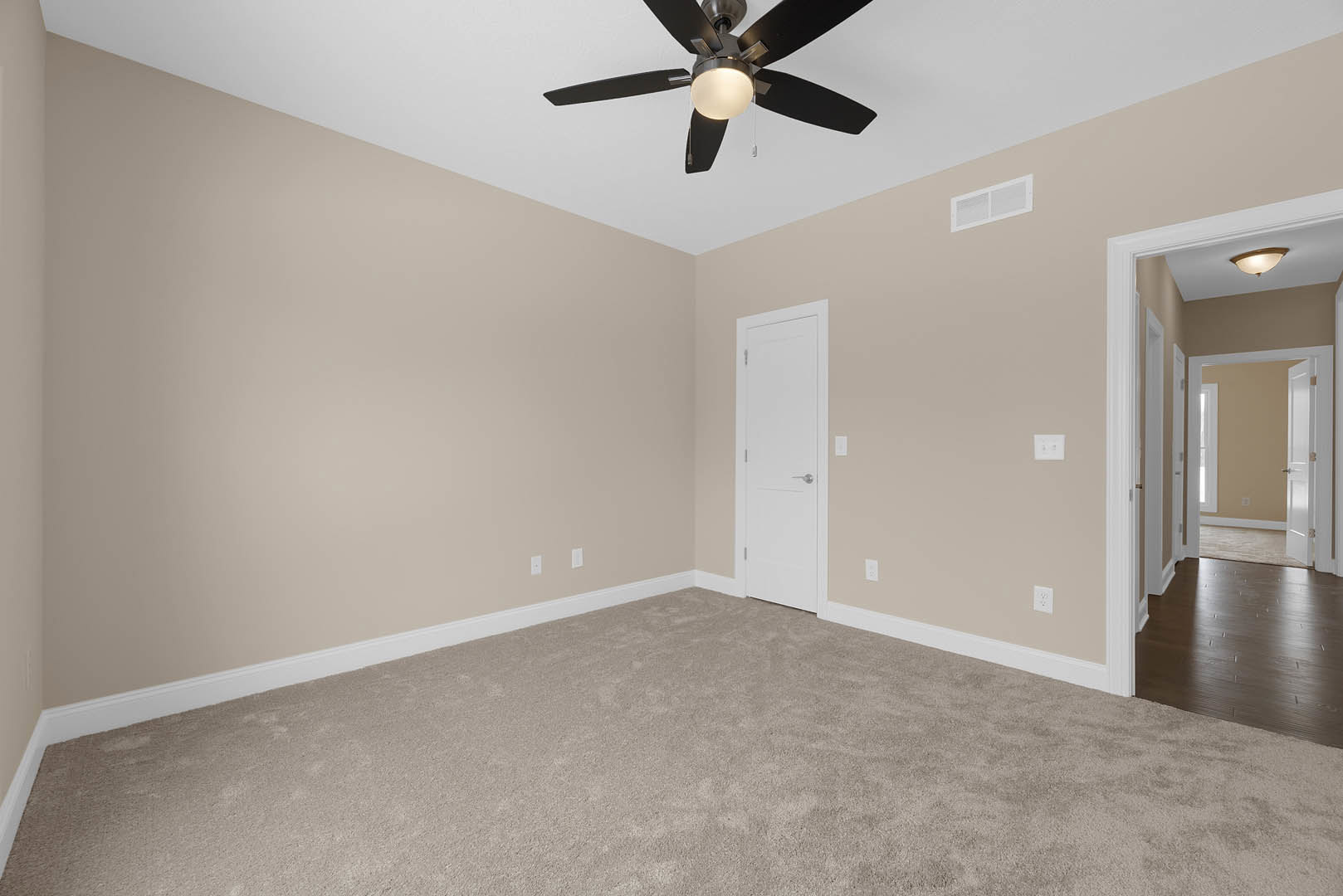 Ceiling fan with light fixture, white paneled door with silver handle, dark wood flooring with white baseboard trim, neutral painted walls, plaster ceiling