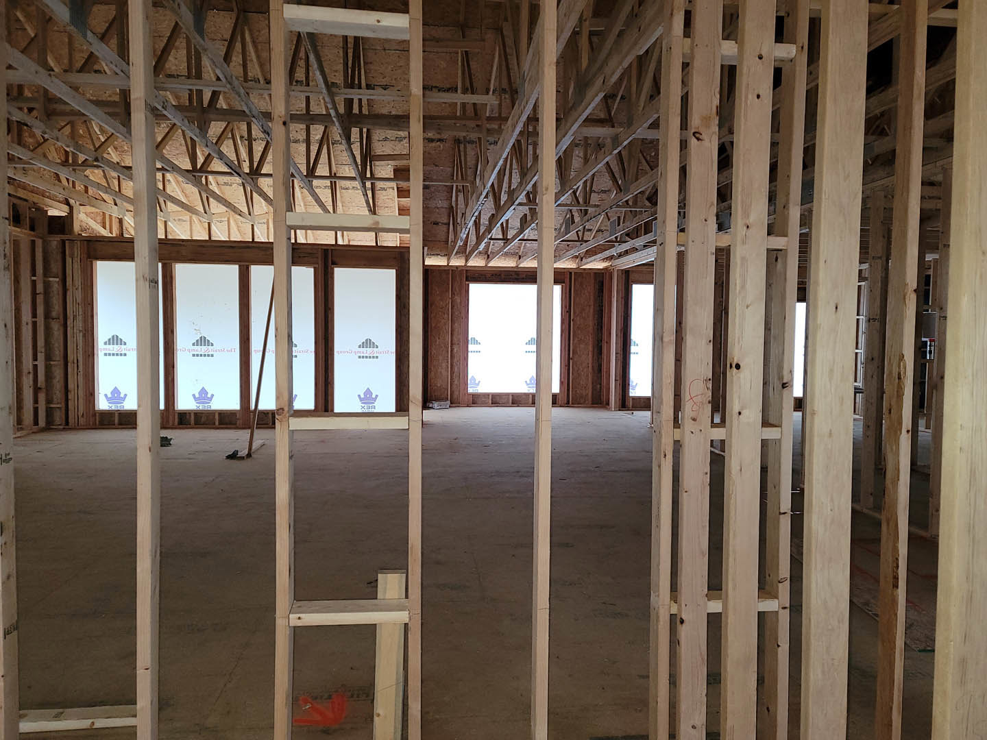 Living room with exposed wood ceiling beams, large windows, and hardwood flooring
