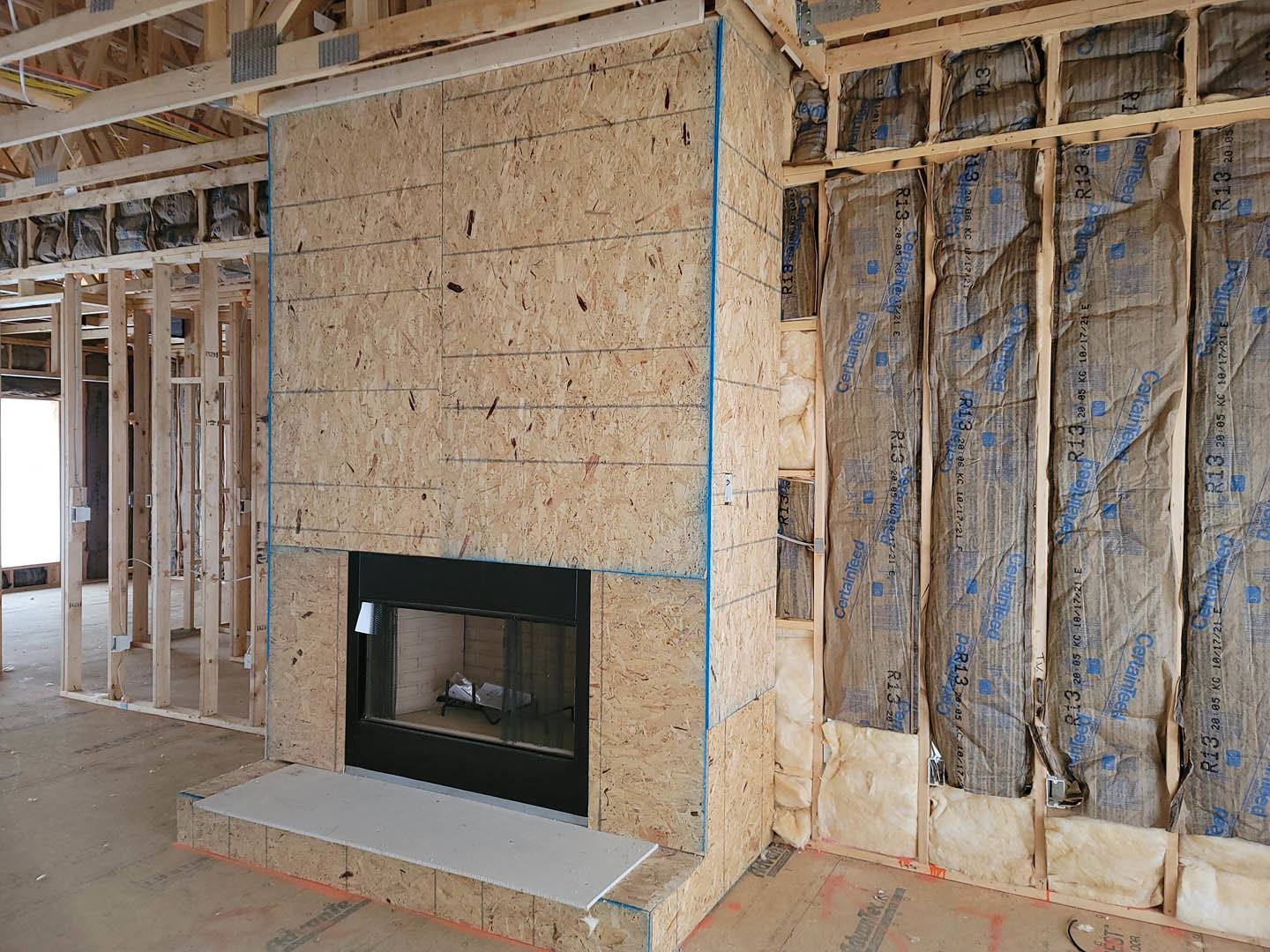 Brick fireplace surrounded by unfinished walls and construction materials on a residential building site