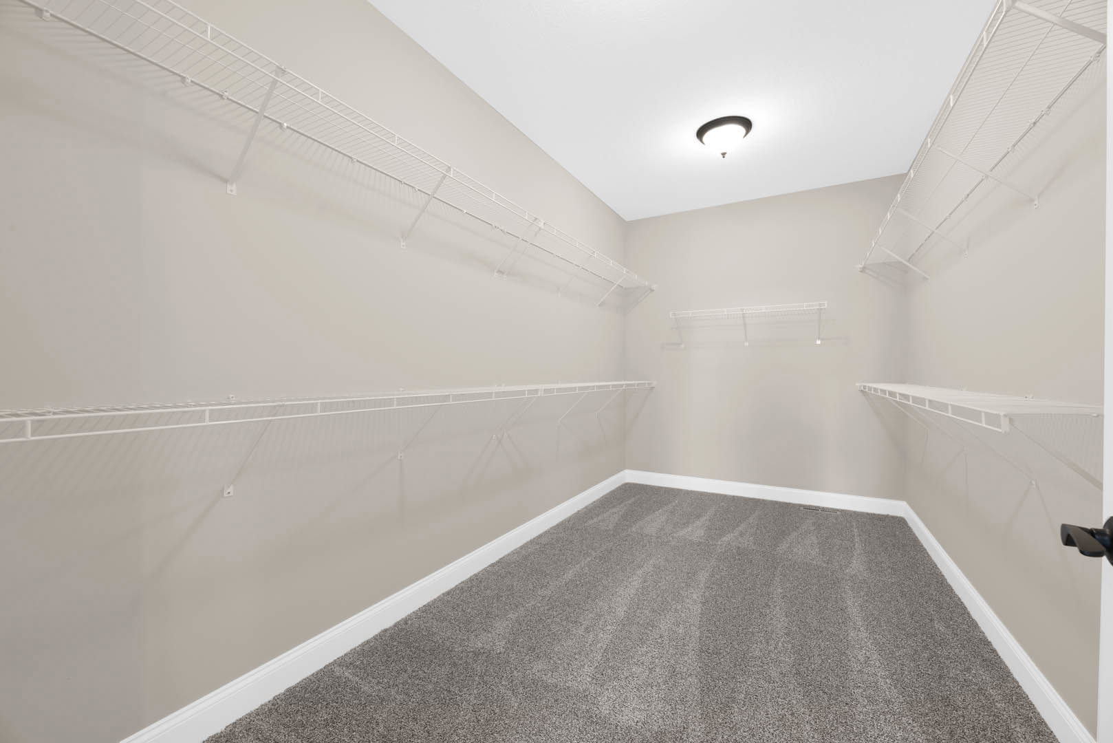 Built-in wall shelves and grey carpet flooring in a room with white plaster ceiling, recessed light fixture, and marble tile accents near a modern faucet.