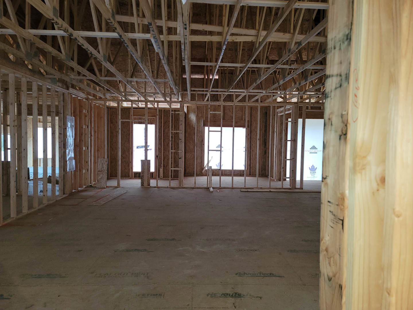Open room with exposed wood ceiling beams, large glass windows, and smooth concrete floor