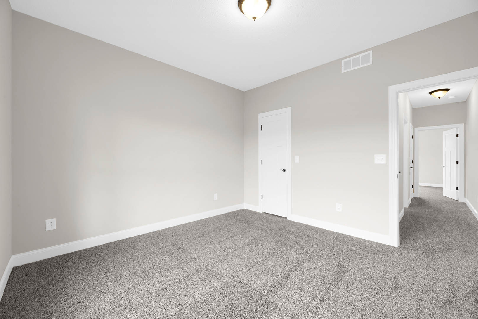 White carpeted room with a white paneled door featuring a silver handle, white walls, and a flush-mounted ceiling light fixture