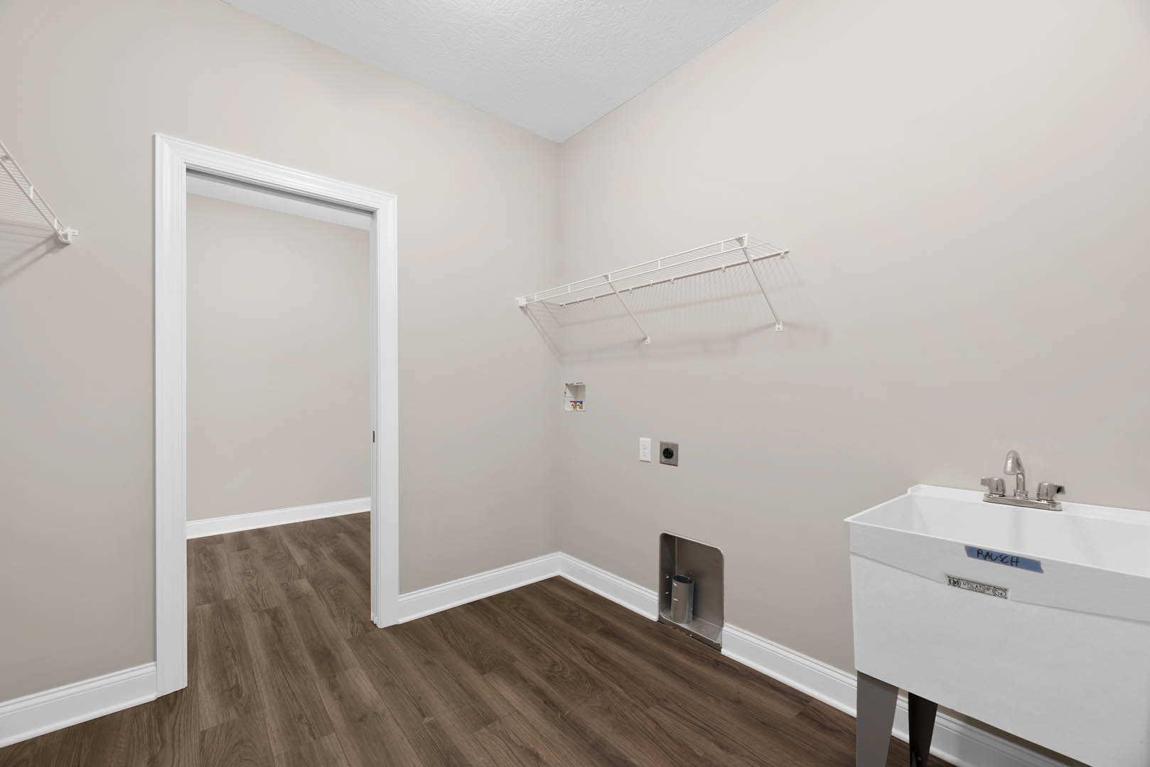 Wood floor room with white sink, white railing along wall, metal cylinder on shelf, white ladder attached to ceiling, plaster walls, and plumbing fixtures.