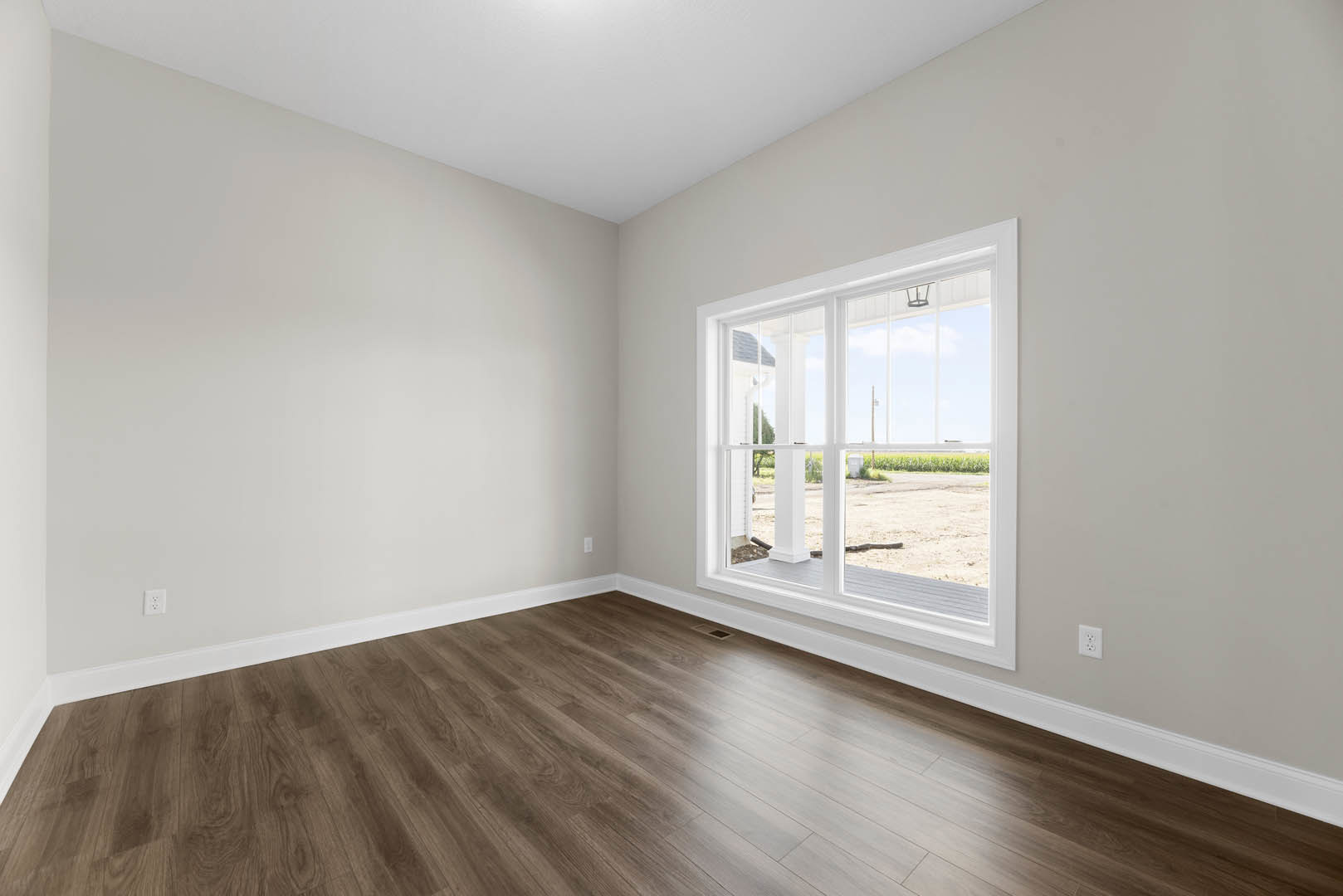 Sunlit room with white plaster walls, large window overlooking farmland, and polished hardwood flooring; snake visible on ground outside window.