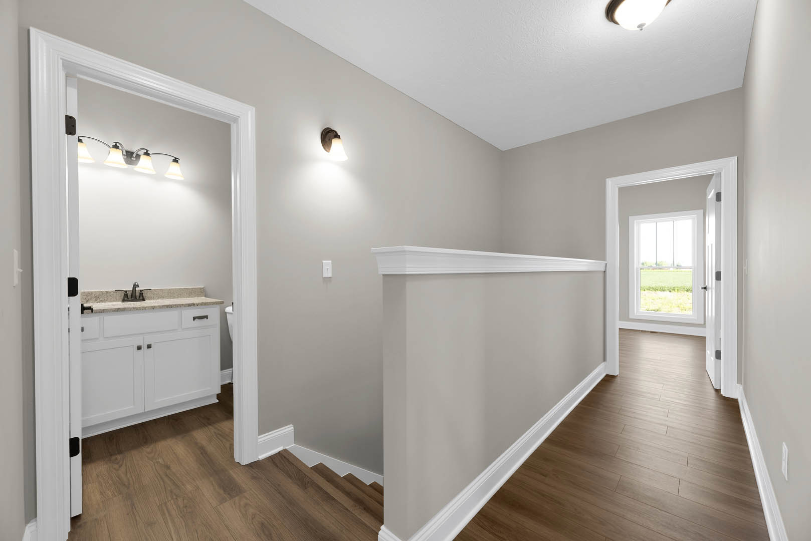 Hallway with light wood flooring, white plaster walls, built-in sink with cabinetry, ceiling light fixture, and window overlooking grassy field