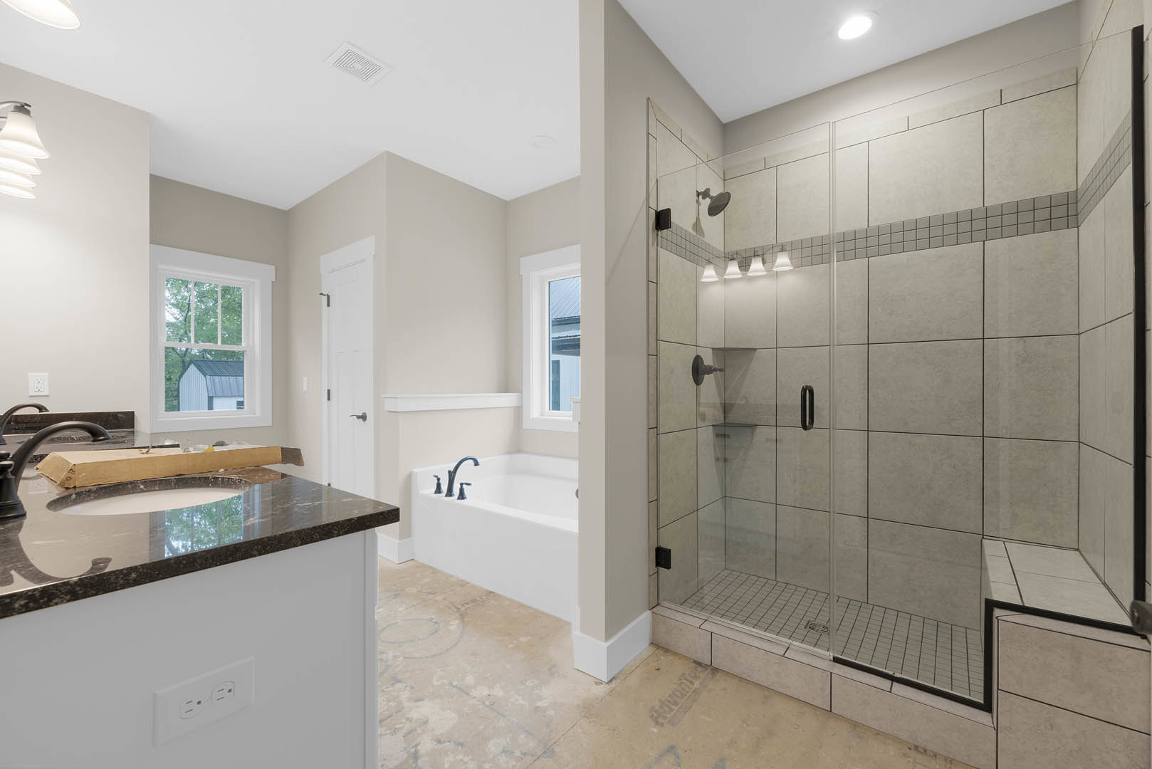 Bathroom featuring a glass-enclosed shower, freestanding bathtub, tile flooring, large window overlooking a barn and trees, ceiling light fixture, white sink with a box on top, and