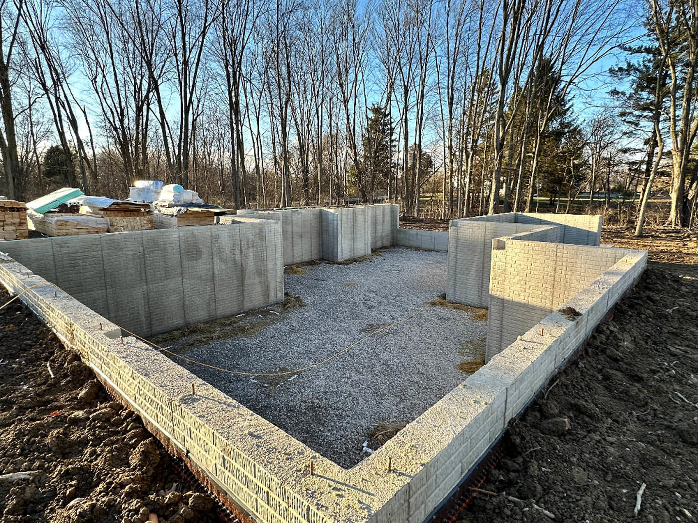 Square concrete foundation surrounded by bare ground and scattered trees under a clear sky