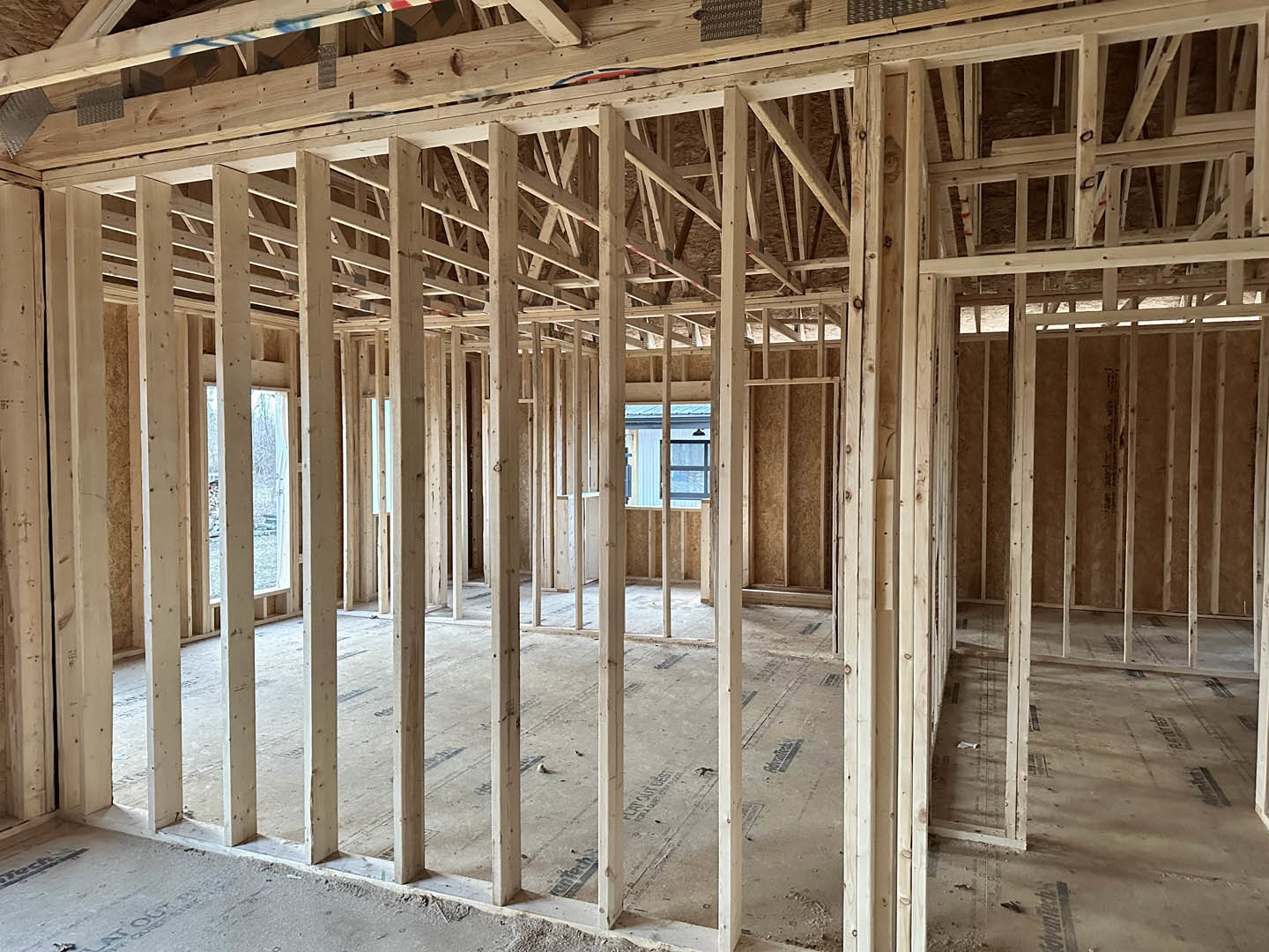 Wood-framed interior under construction with exposed beams, lumber, and concrete floor
