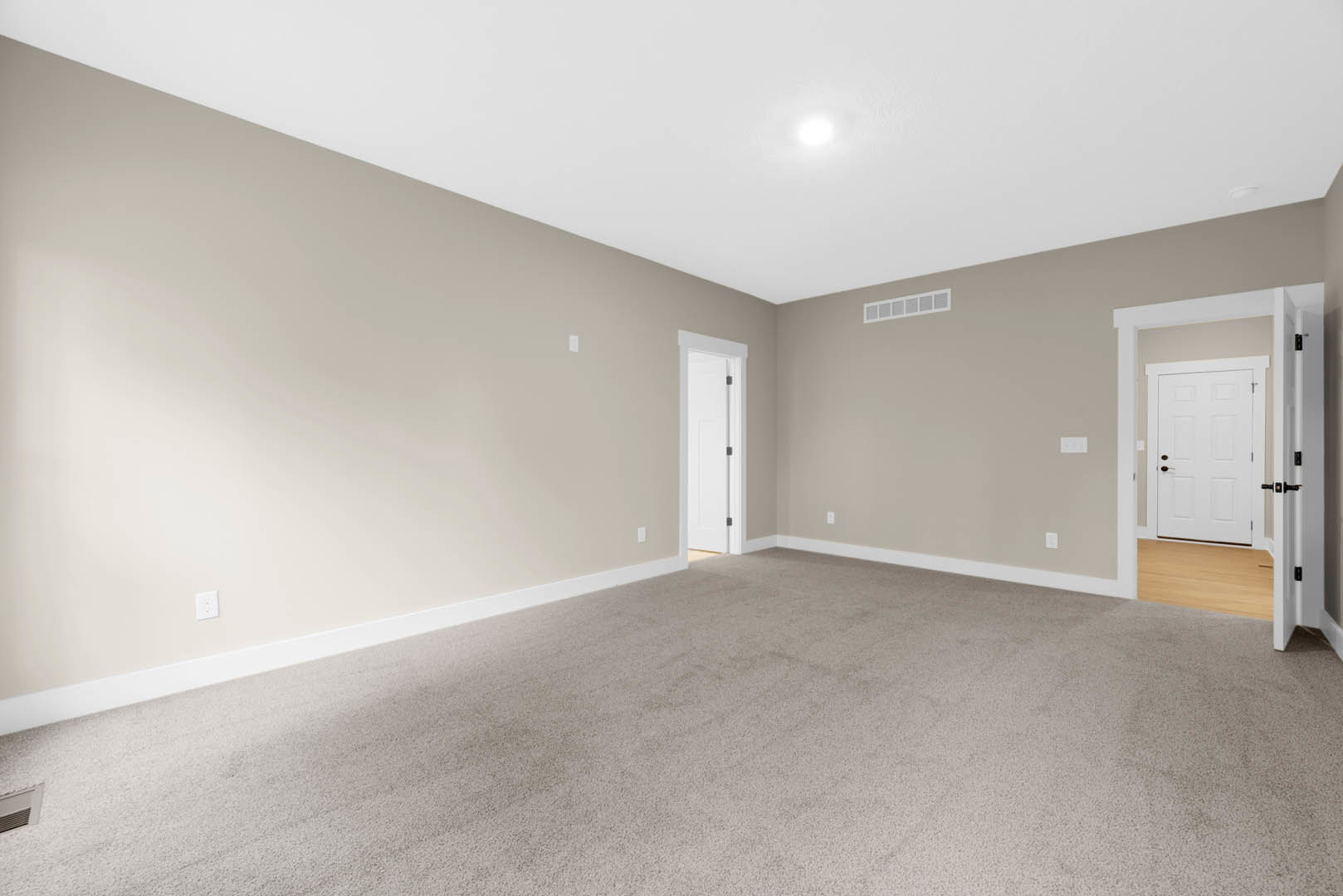 Carpeted room with white door open, brown handle, white walls, and ceiling