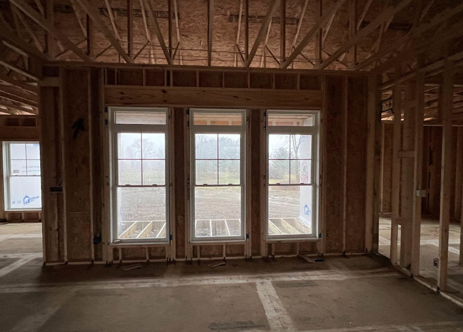 Spacious room featuring large windows, smooth concrete flooring, exposed ceiling beams, and natural daylight illuminating minimalist interior.