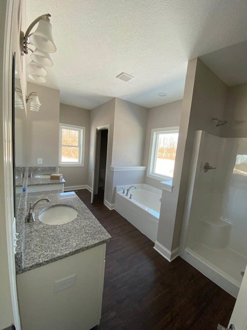 Modern bathroom featuring a freestanding white bathtub, wall-mounted sink with chrome faucet, light gray tile flooring, and a large window with natural light.