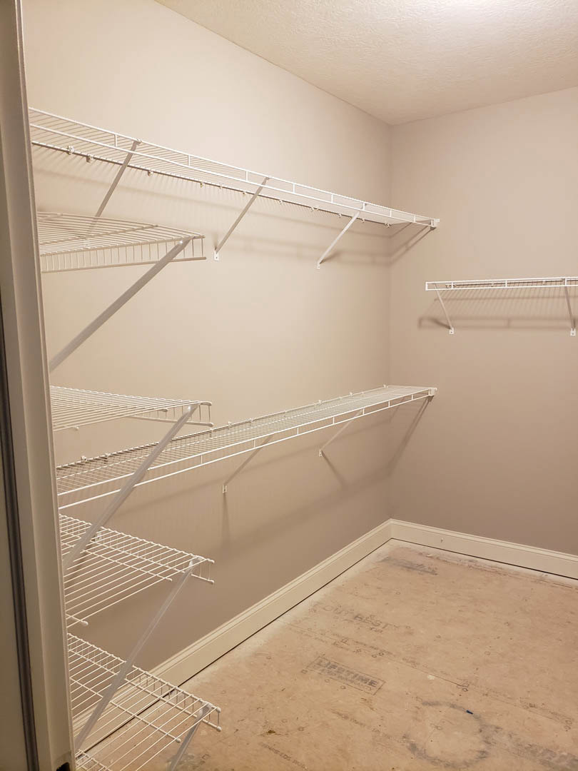 Bathroom with built-in white shelves, white metal towel bar, light gray tile floor, plaster walls, and walk-in shower.