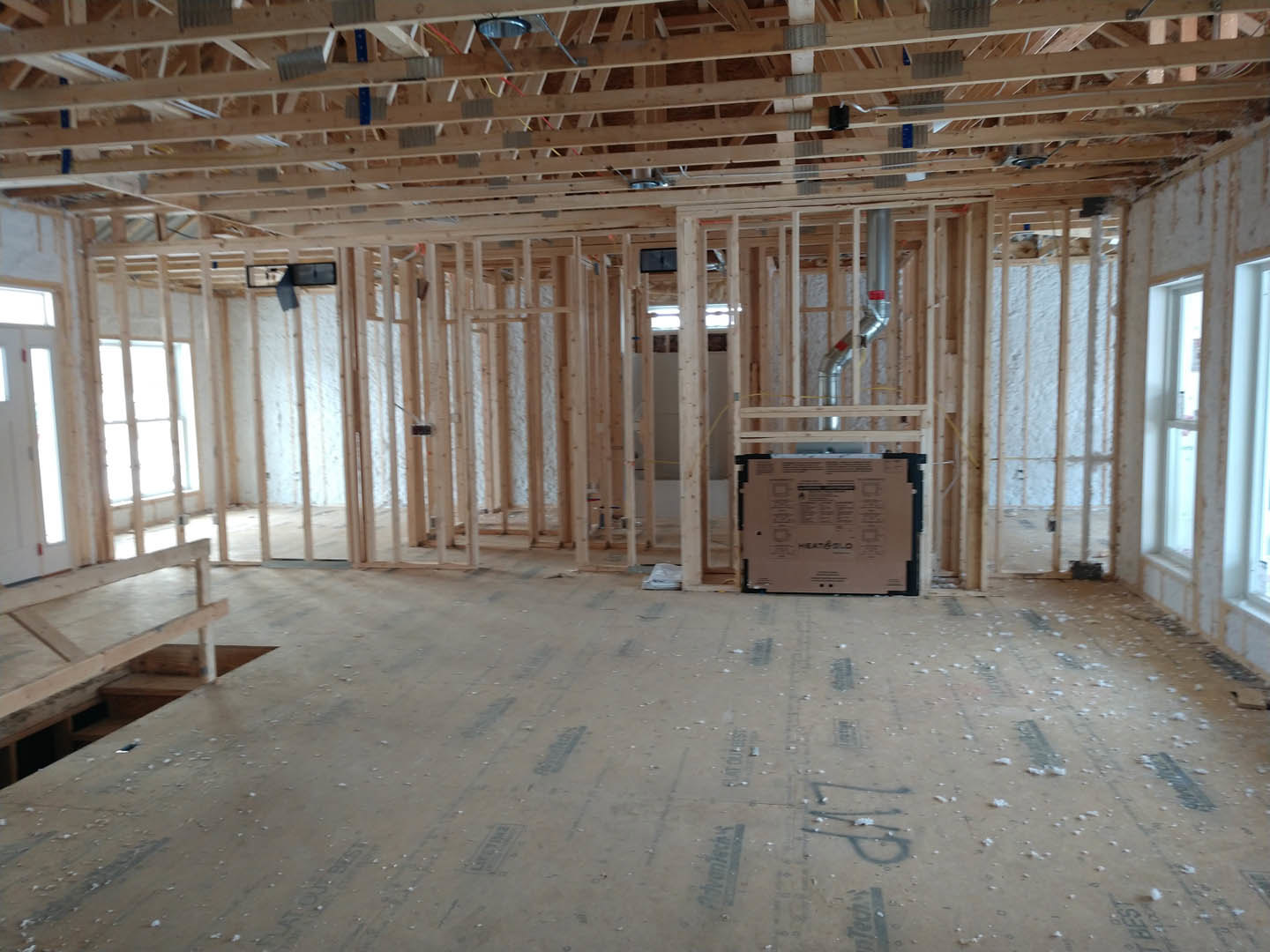 Exposed wood ceiling beams, large window, unfinished floor with cardboard boxes, metal pipe along wall