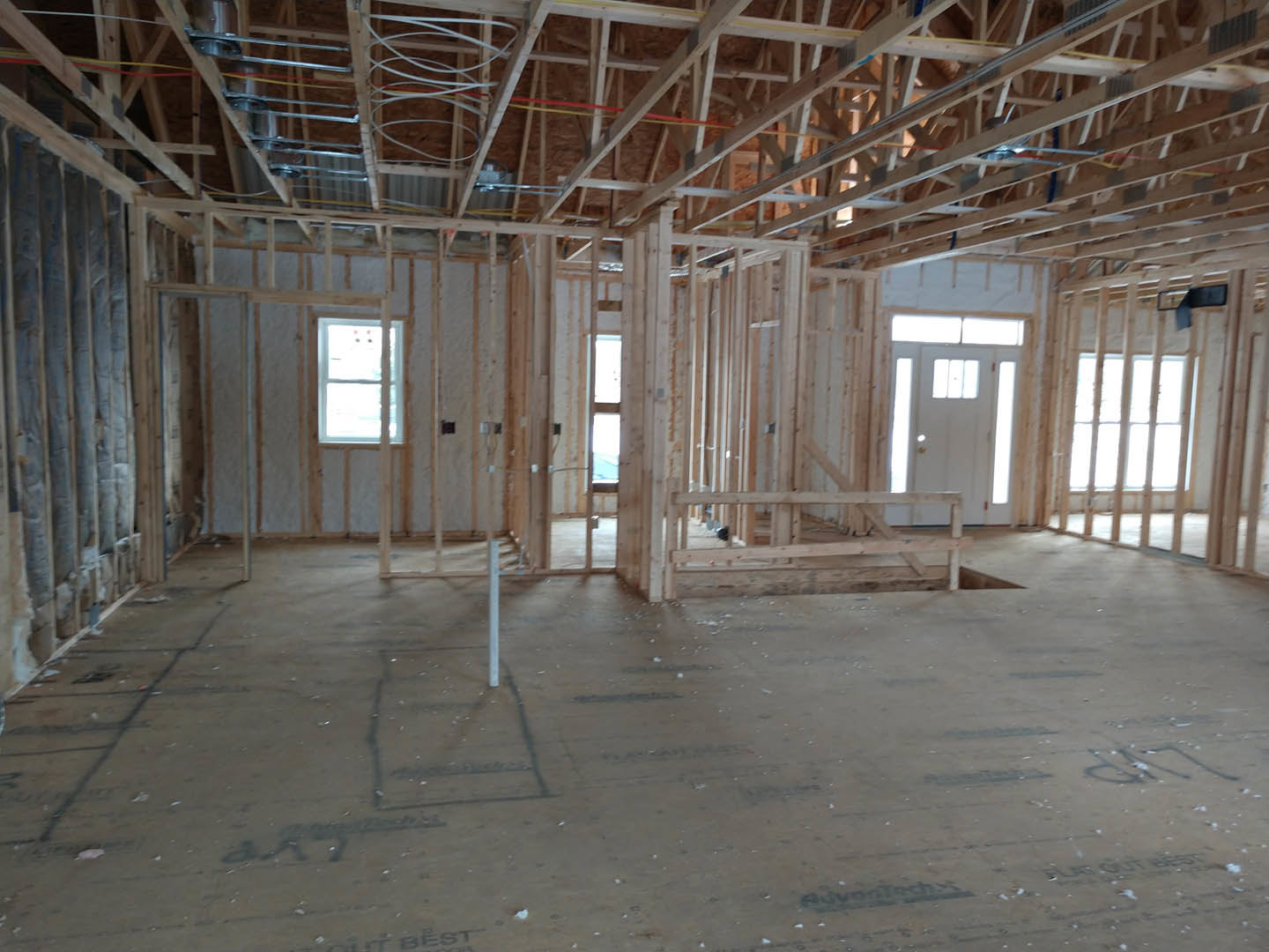 Living room with exposed wood ceiling beams, white framed window, and white door with glass inset