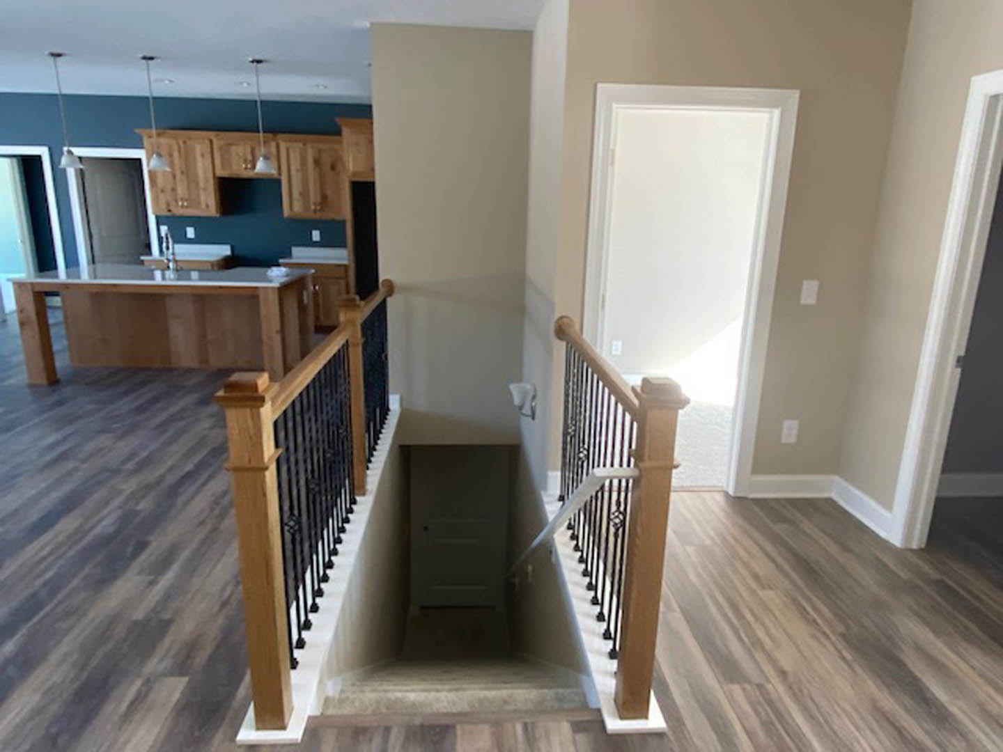 Wood staircase with white railing and laminate flooring, adjacent to a white door in a residential interior.