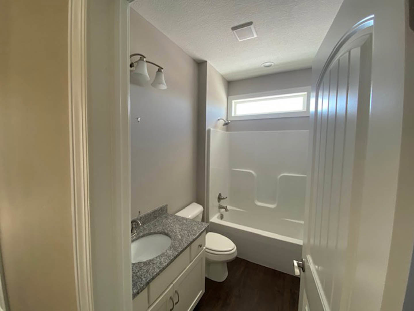 Modern bathroom with white porcelain sink, wall-mounted mirror, ceramic toilet, and freestanding bathtub, surrounded by light gray tile walls and floor