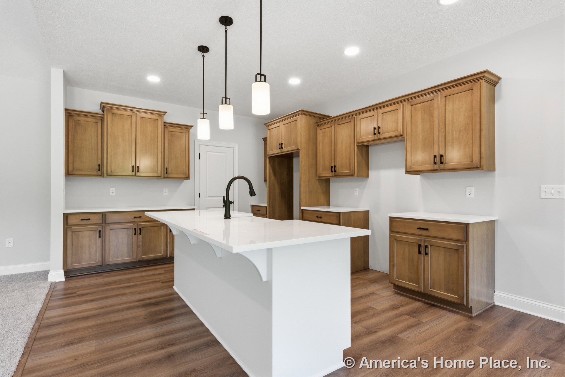 Wood cabinetry with upper and lower storage, white quartz countertops, large central kitchen island, pendant lights above island, recessed ceiling lighting, wood-look flooring