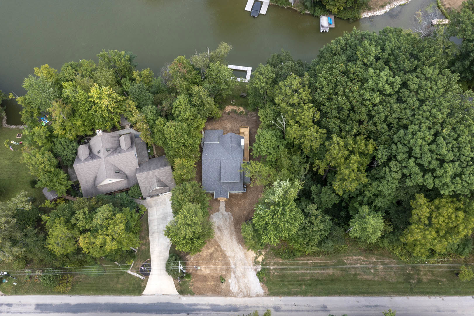 Modern home with gray roof nestled among tall trees, overlooking a winding river, lush greenery surrounding the property