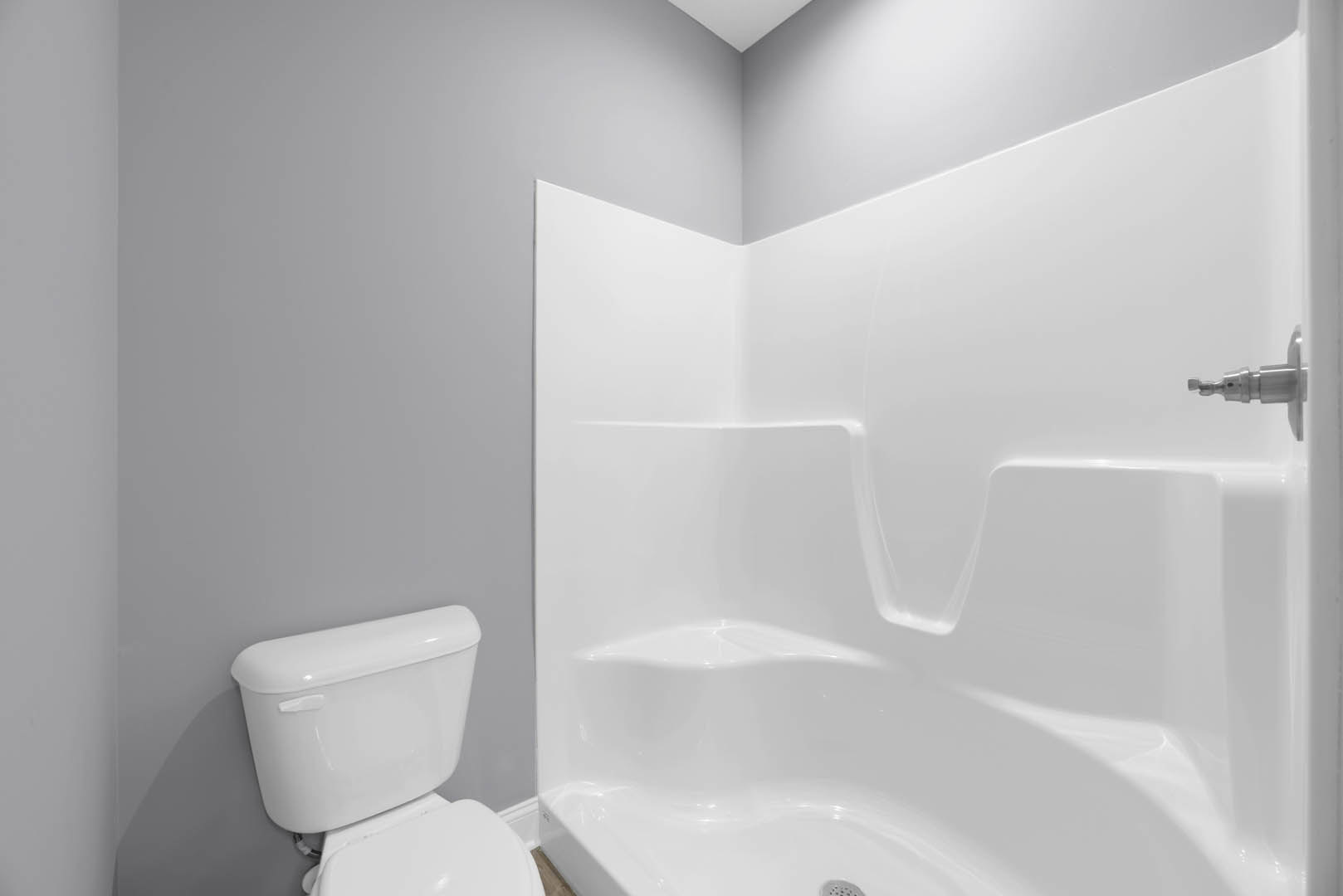 White bathtub and toilet against light gray tiled wall in modern bathroom
