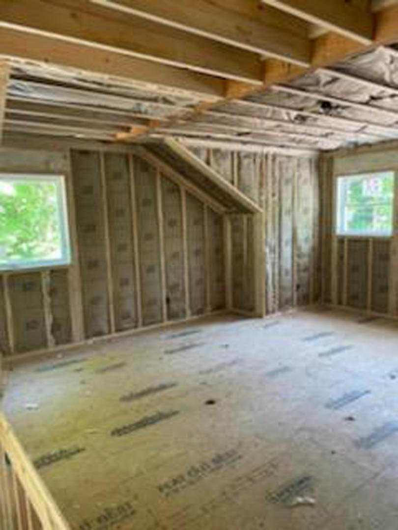 Spacious room featuring hardwood floors, large windows, wood beam ceiling, and neutral walls