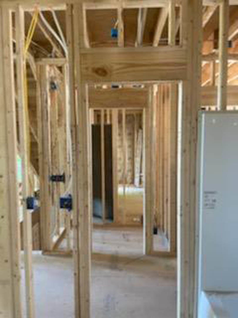 Exposed wood framing and beams in a partially constructed home interior with visible insulation and unfinished walls