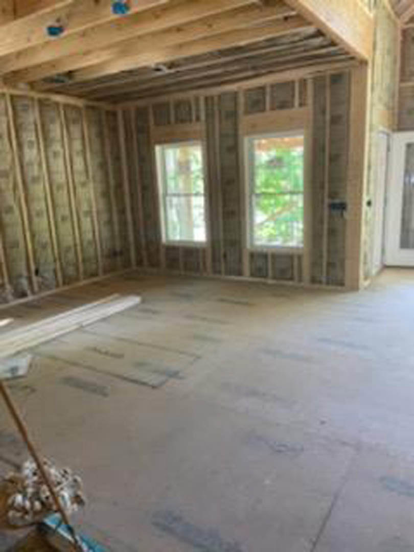 Living room with exposed wood ceiling beams, large windows, hardwood flooring, and white walls