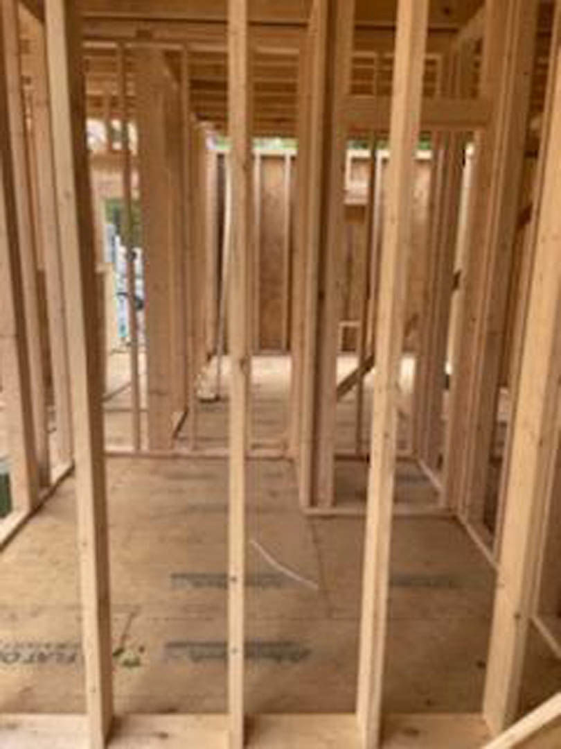 Exposed wooden framing and beams inside a residential construction site with unfinished walls and visible insulation