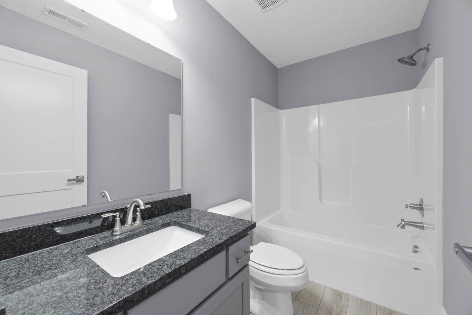 Modern bathroom featuring a white ceramic sink with chrome faucet, glass-enclosed shower with tile walls, and a sleek toilet adjacent to a black-bordered vanity.
