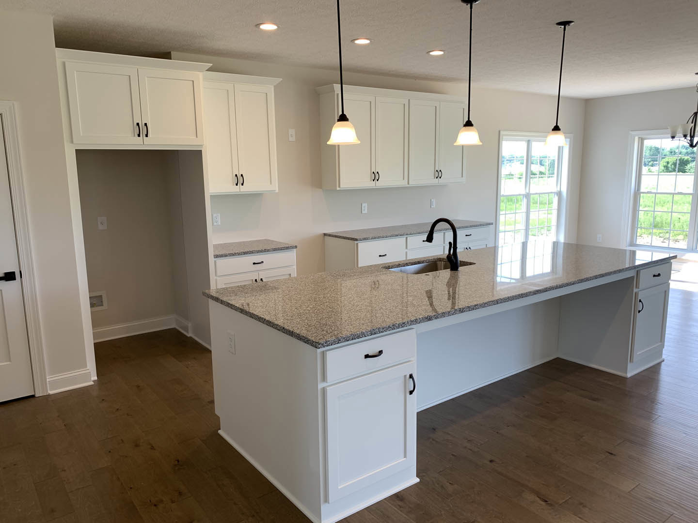 Granite countertop kitchen with white cabinets, stainless steel sink, tile backsplash, ceiling light, and window overlooking grassy yard