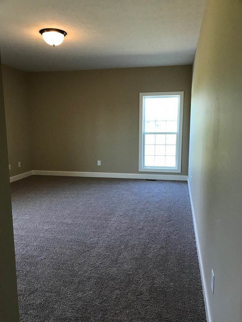 Carpeted room with white walls, large window with white frame, ceiling light fixture, and plaster ceiling