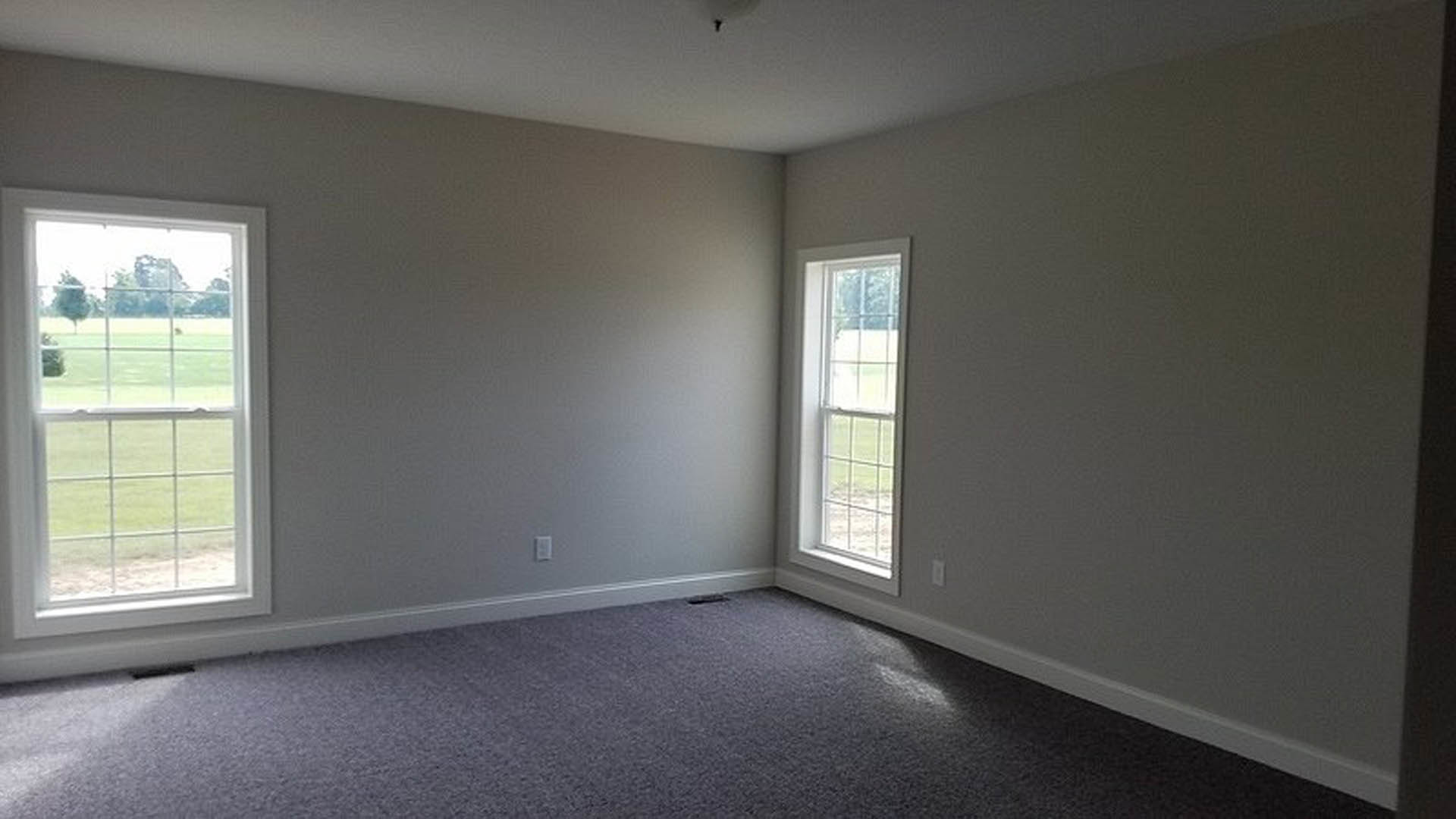 Bright interior room featuring a large window, light-colored walls, hardwood flooring, and natural daylight illuminating the space.