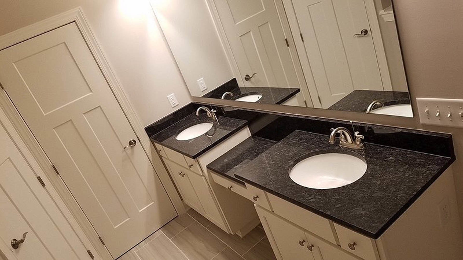Double vanity with rectangular mirrors, white vessel sinks, chrome faucets, light gray tile backsplash, and wood cabinetry.