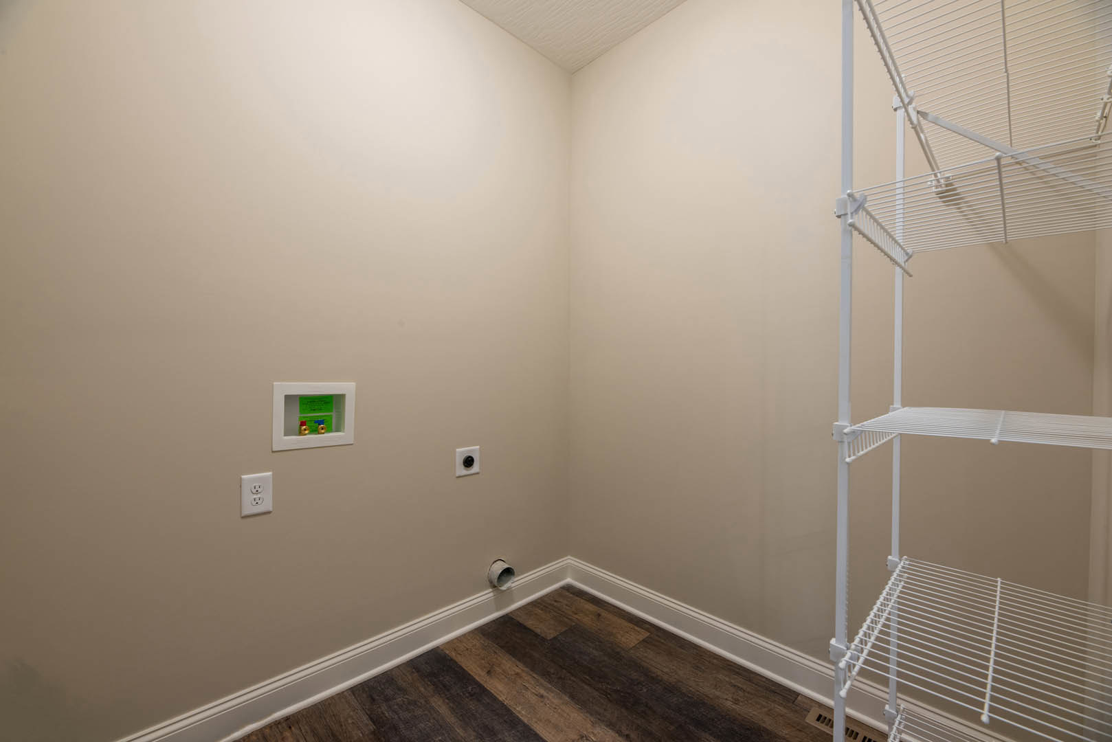 White floating shelf mounted on plaster wall above light wood floor in minimalist room