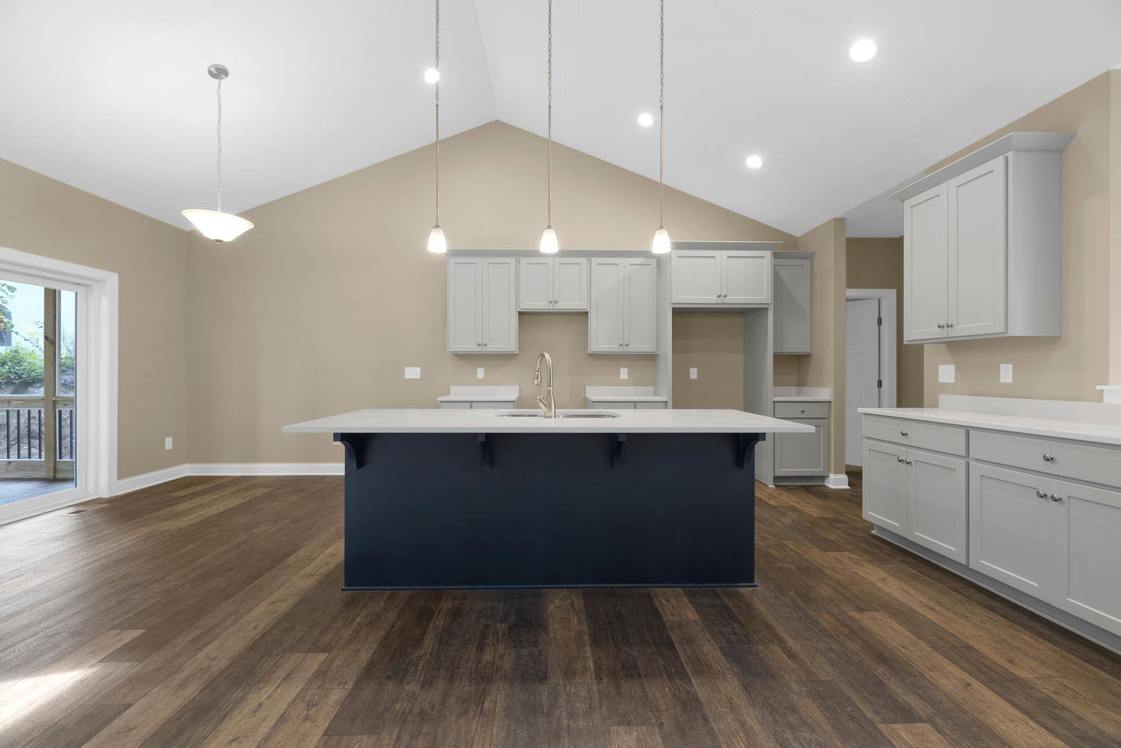 Spacious kitchen featuring a large white island with integrated sink, dark wood flooring, black accent wall, white cabinetry, and tile backsplash