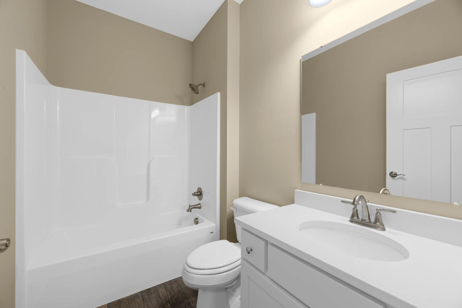 White bathroom featuring a rectangular sink with chrome faucet, wall-mounted mirror, white toilet, tiled walls, and partial view of a bathtub with showerhead.