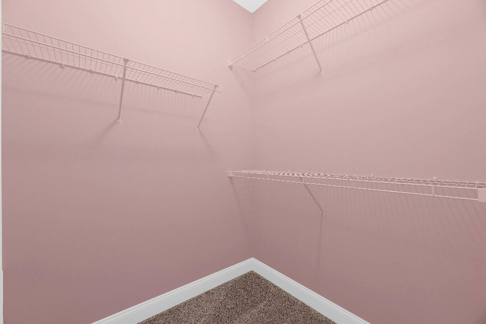 Pink plaster walls with built-in white shelves, soft carpet flooring, and a white surface detail in a residential interior room