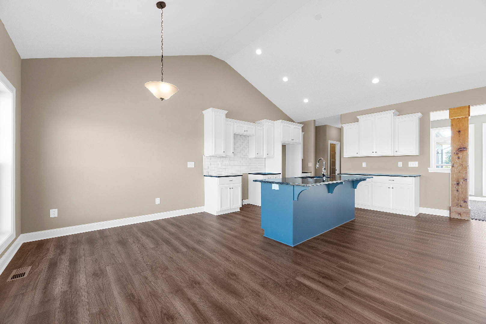 Blue kitchen island with marble countertop, white wall cabinets, hardwood flooring, and floor vent visible.