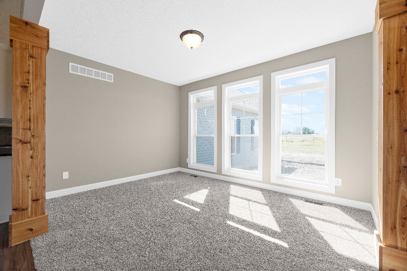 Carpeted room with large windows, white walls, wood trim, and natural light illuminating the space
