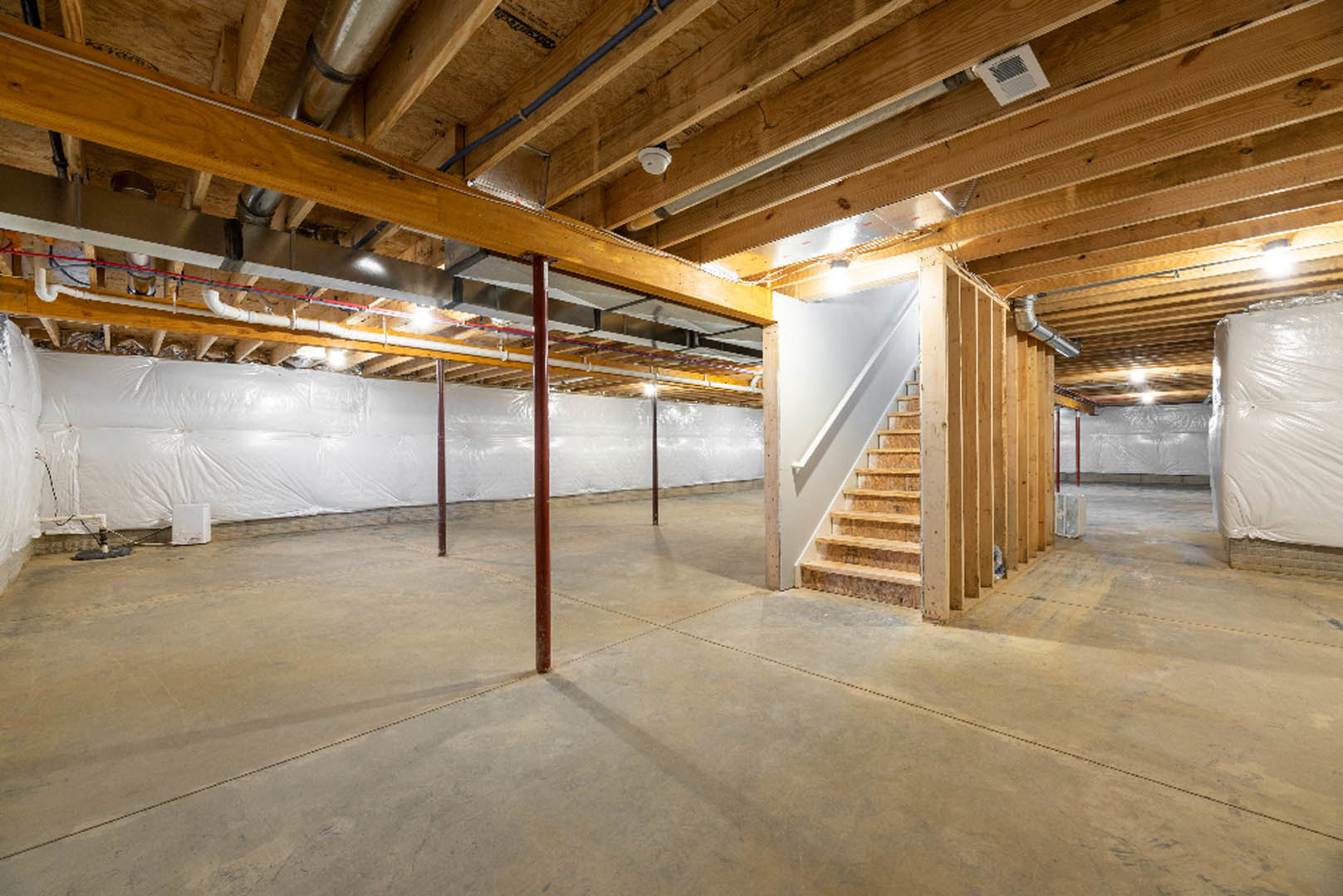 Basement with exposed wooden ceiling beams, concrete floor, red support pole, white staircase, and visible ceiling vent